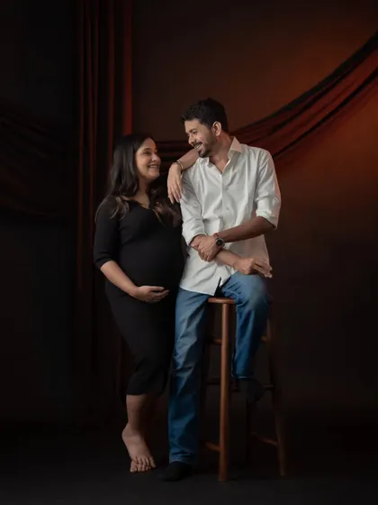 A stylish and classic couple's portrait against a dark, dramatic backdrop. Their interaction is natural and full of affection, creating a timeless memory.