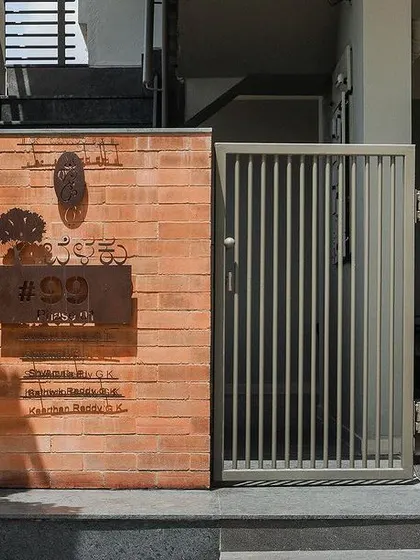 The entrance detail of 'House Belaku', where a small brick wall and a custom nameplate welcome visitors.