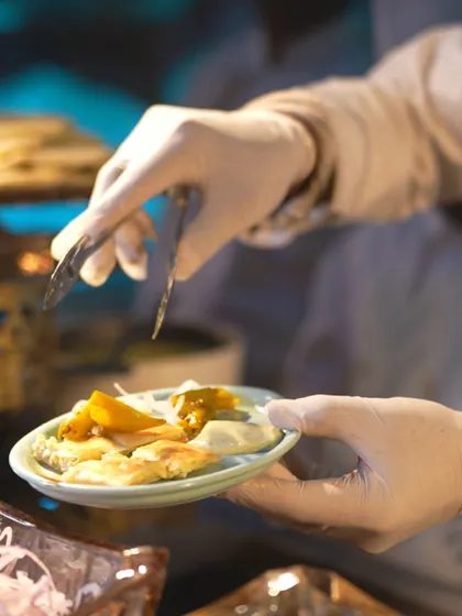 A guest's plate being carefully filled by one of our servers. This image emphasizes the personal and attentive service we provide, ensuring every guest feels valued.