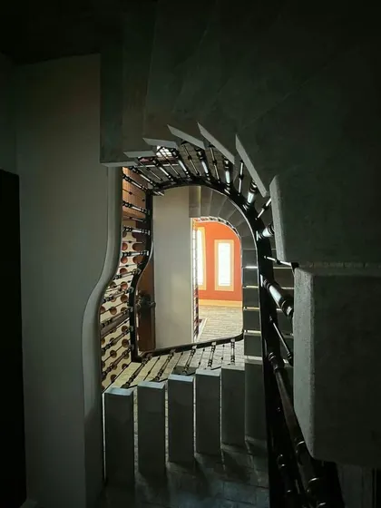 A view through the curved opening of a staircase reveals the interconnectedness of the home's spaces. This design approach avoids solid walls where possible, enhancing the sense of openness and flow.