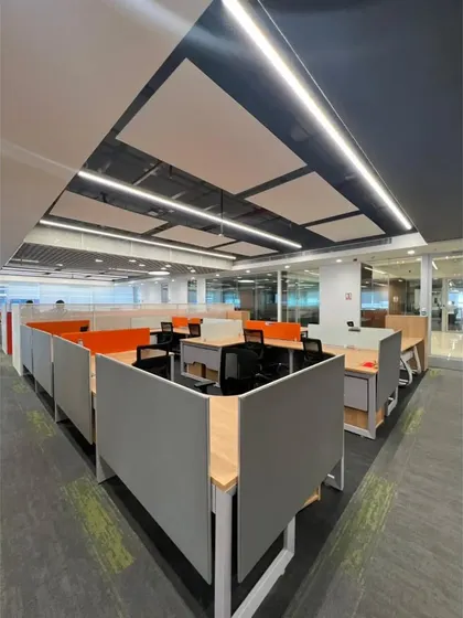 A view of the workstation cubicles with orange accent panels. The angular arrangement of the partitions breaks the monotony of a typical grid layout, adding a dynamic quality to the workspace.
