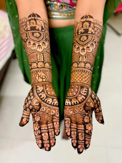 This royal-themed bridal mehendi includes the couple's initials, "KP," set within a decorative frame. The design is filled with elephants and palanquin motifs.