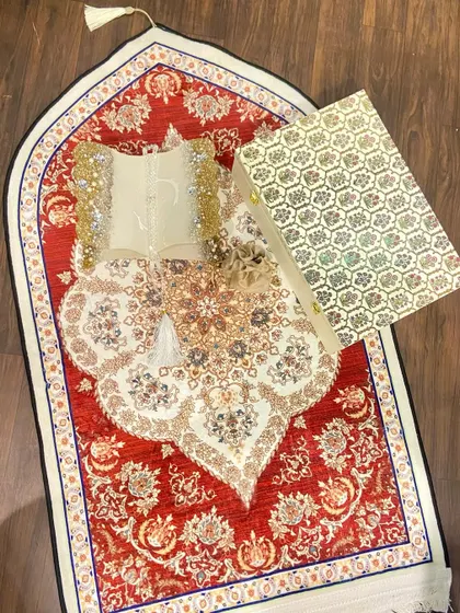 A beautiful Ramadan gift set featuring a dome-shaped prayer mat with an intricate red and white design. The set includes a custom Quran holder and a crystal tasbeeh, making it a perfect gift for the holy month.