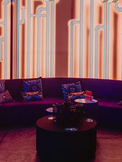 Even the lounge areas were on-theme. We used a purple velvet sofa set against a backlit wall with a graphic pipe design, creating a cool, industrial-chic vibe.