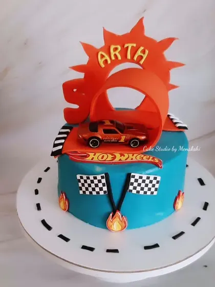 A Hot Wheels themed cake for a 5th birthday. I created the iconic orange track loop for the car to race through, complete with checkered flags.