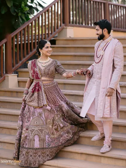 A grand entrance. This shot captures the couple's regal presence and the bride's unique, story-telling lehenga.