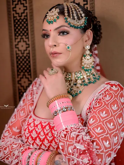 A close-up shot focusing on the bride's expressive eyes and jewellery. The way she holds her hand near her face draws attention to her bangles and hath phool.