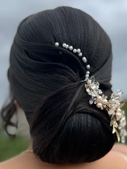 The final look of the sleek bun, adorned with a beautiful crystal and pearl hair vine. This is a very popular style for modern brides.