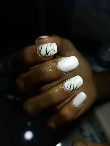 A close-up of these chic marble nails. The design features a white base with black and gold veins, creating a sophisticated look that mimics real marble stone.