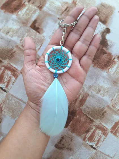 A simple and elegant dreamcatcher keychain with a single feather. This evil eye design is perfect for adding a touch of protective charm to your keys or bag.