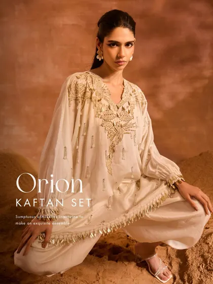 A closer look at the Orion Kaftan Set. This ensemble pairs a luxuriously embellished kaftan with contemporary solid dhoti pants, showcasing phoenix-inspired motifs and pearl-infused tassels for a relaxed yet chic statement.