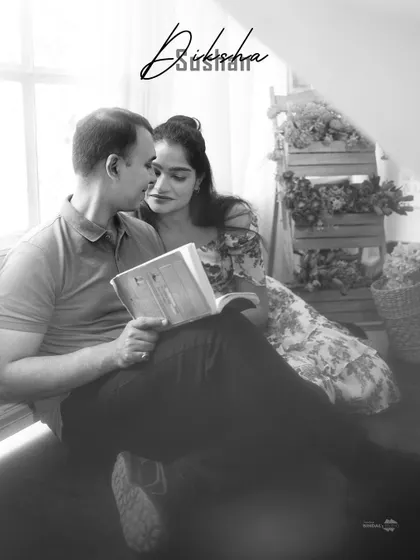 A quiet, intimate moment captured in black and white. The couple sharing a book creates a narrative of shared interests and comfortable companionship.