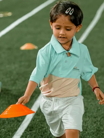 A child runs with a cone, focused on his task during a Sports Day relay race.