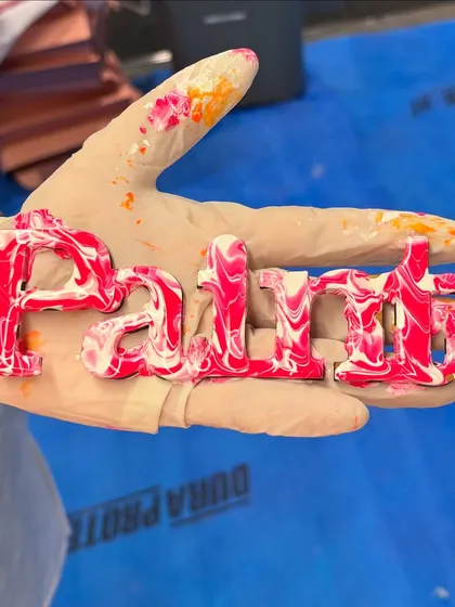 A close-up of a "Paint" sign created with the fluid art technique. The pink and white marble effect is so pretty.
