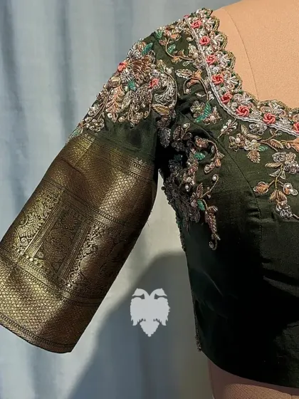 A close-up of the shoulder of the olive green blouse, engraved with a floral and creeper design.