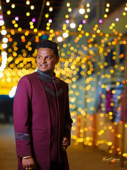 A candid portrait of the groom against a backdrop of golden bokeh lights, looking happy and relaxed.