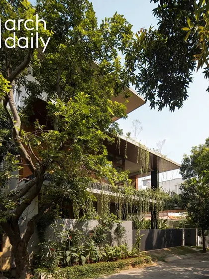 A street-level view from ArchDaily, showing the house nestled among the trees.