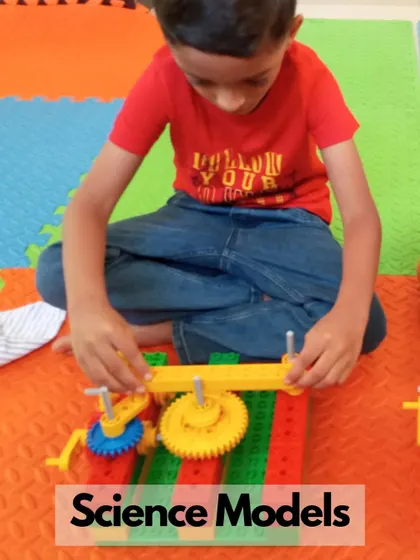 A young boy is deeply focused on his science model, figuring out how different gears mesh together. This hands-on exploration is the foundation of mechanical understanding.