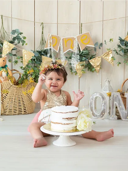 A sweet and slightly messy portrait from a first birthday cake smash. The combination of a sequined dress and a simple cake makes for a lovely, celebratory photo.
