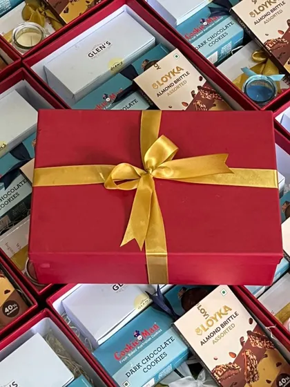 A close-up of a finished corporate gift box, wrapped in vibrant red paper with a perfectly tied golden ribbon, ready to make a lasting impression.