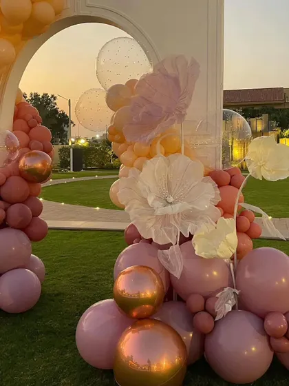 A stunning balloon arch in shades of dusty rose, peach, and metallic copper, accented with large, ethereal paper flowers for a romantic bridal shower.