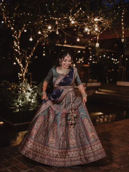 The bride twirls in her magnificent lehenga, the fairy lights creating a magical, dreamlike backdrop for this nighttime portrait.