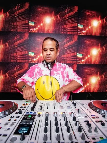 Ace of the Bass. A straight-on shot of me at my Pioneer controller, with a massive smiley face on my shirt, ready to drop cái bass.