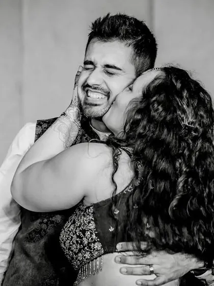 A playful and affectionate kiss on the cheek, captured in timeless black and white. The groom's scrunched-up, happy face is priceless.