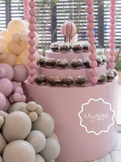 A tiered display stand for the terrarium favors, beautifully integrated with a pastel balloon garland.