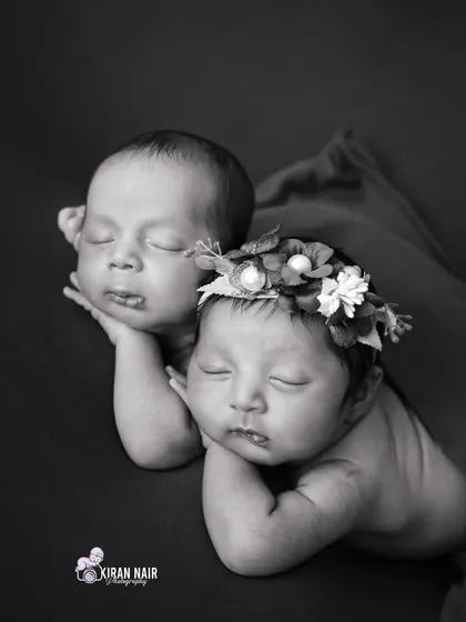 A beautiful black and white portrait of newborn twins, posed cheek to cheek. This emphasizes their connection and similar features.