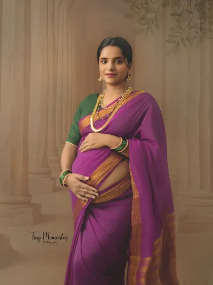 Dressed in a vibrant purple Mysore silk saree, this portrait captures the regal elegance and quiet strength of a mother-to-be.