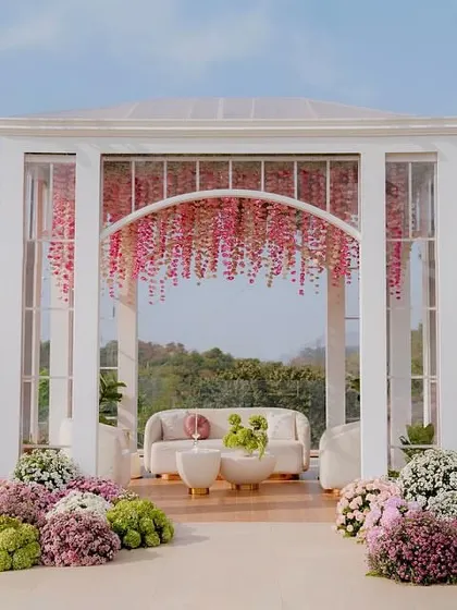 A beautiful glasshouse structure served as the mandap for this intimate Lagan Lakhwanu ceremony. Adorned with a curtain of pink flowers, it created a picturesque frame against the green hills.