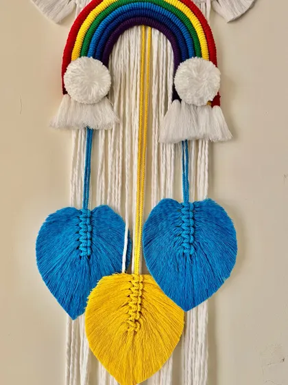 A close-up of the hanging leaves on this vibrant rainbow name hanging.
