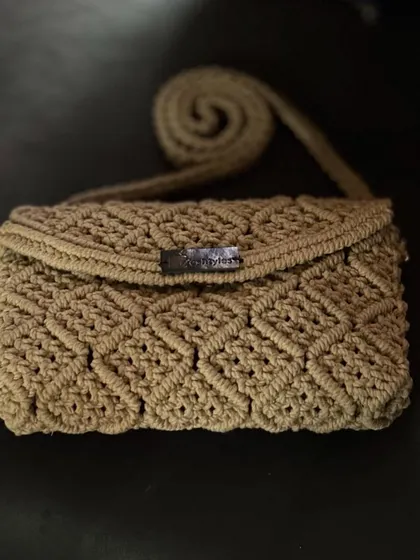 A straight-on shot of the beige clutch, showcasing the detailed craftsmanship.