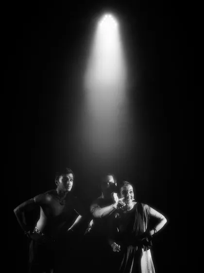 A black and white shot of the dancers in 'Naga Mandala' under a single spotlight. The composition emphasizes their unity and shared fate.