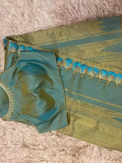 The front of the sleeveless teal blouse, showing the delicate embroidery around the neckline.