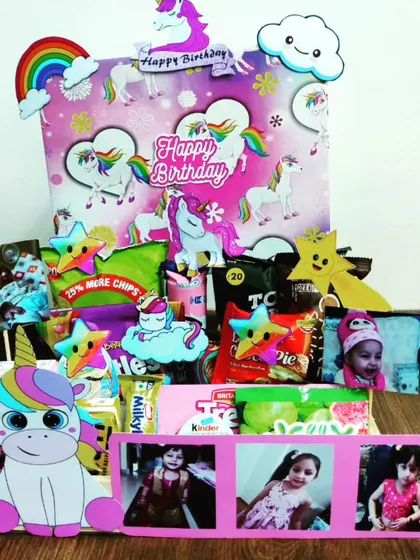 A magical unicorn-themed hamper designed to delight. This gift is filled with snacks and personalized with photos, all surrounded by cute unicorn, rainbow, and cloud decorations.
