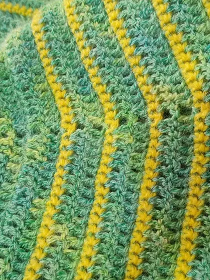 A close-up of the stitch pattern on the green and yellow shawl. The simple stitches allow the beautiful colors of the yarn to be the main focus.