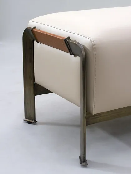 A detail of the chaise, showing the elegant metal frame with a leather-wrapped accent, a small touch that adds a lot of luxury.