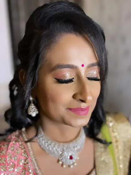 For this gorgeous reception look, we went with full-on glam. I created a sparkling glitter eyeshadow look with winged liner and a bright pink lip, paired with soft curls for a festive and modern style.