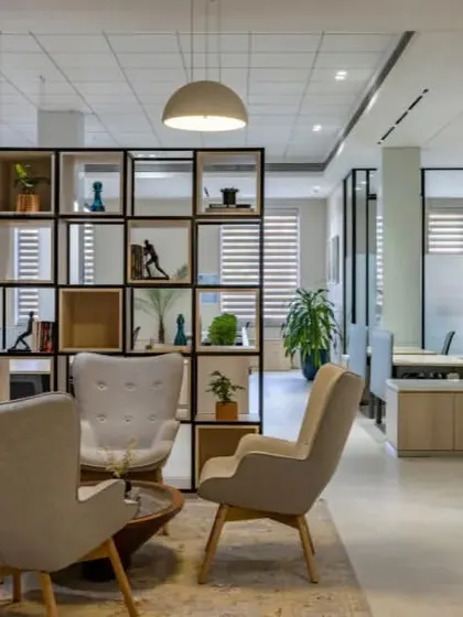 The open-backed shelving unit in this lounge acts as a functional piece of art, dividing the space while allowing light to pass through and providing surfaces for decorative objects.