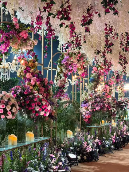 A closer look at the melange of florals. This walkway is lined with candles and an abundance of flowers in shades of purple and pink, creating an immersive and romantic path.