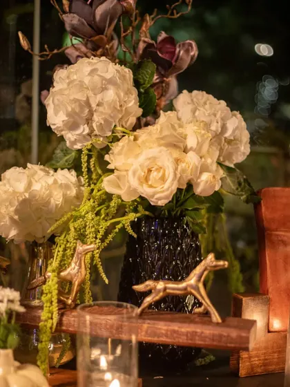 A close-up detail from the cocktail night, showing a mix of white hydrangeas and roses in a dark vase, accented by small golden horse figurines. These small, thematic touches are what make our designs unique.