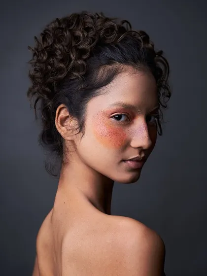 This is makeup as art. I used a wash of warm, diffused color across the eyes and cheeks, adding faux freckles for a unique, sun-kissed look that feels both natural and conceptual.