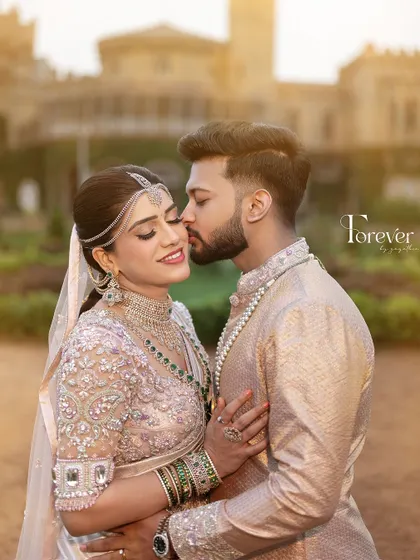 A sweet and intimate moment. The groom, dressed in a custom pastel sherwani, shares a happy moment with his bride, showcasing the joy of their special day.