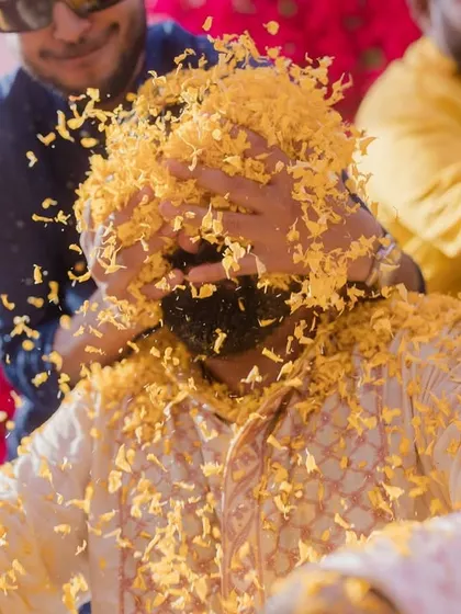 A close-up of the groom getting completely covered in flower petals during his Haldi, a shot that perfectly captures the joyful chaos.