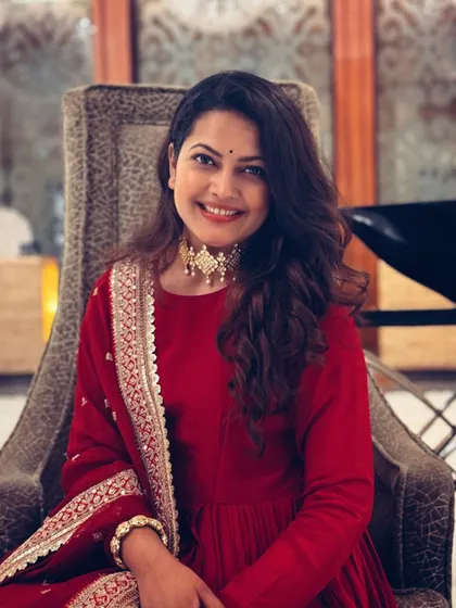 A relaxed portrait of Priyanka Barve, showing the beautiful choker necklace paired with the red Anarkali.