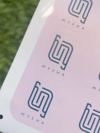 A close-up of the custom circular stickers I designed for @_labelmysha_, featuring their brand logo on a soft pink background.