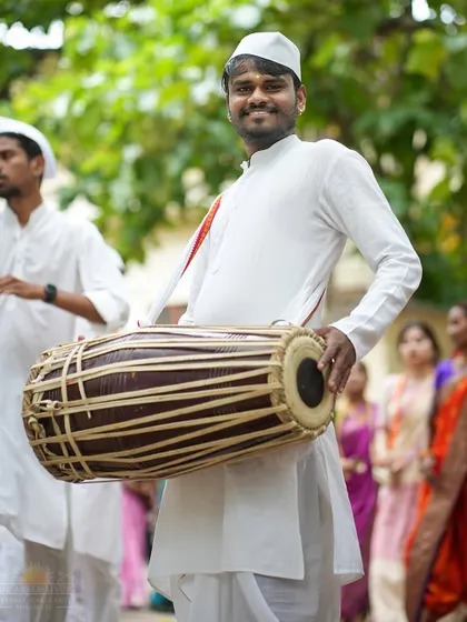 A devotee plays a traditional drum during the Ashadhi Ekadashi procession. The rhythmic beats create a powerful, meditative, and celebratory atmosphere.