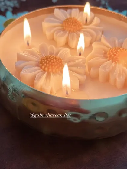 The daisy urli candle, lit and casting a warm, inviting light. This is a perfect centerpiece for any festive occasion.